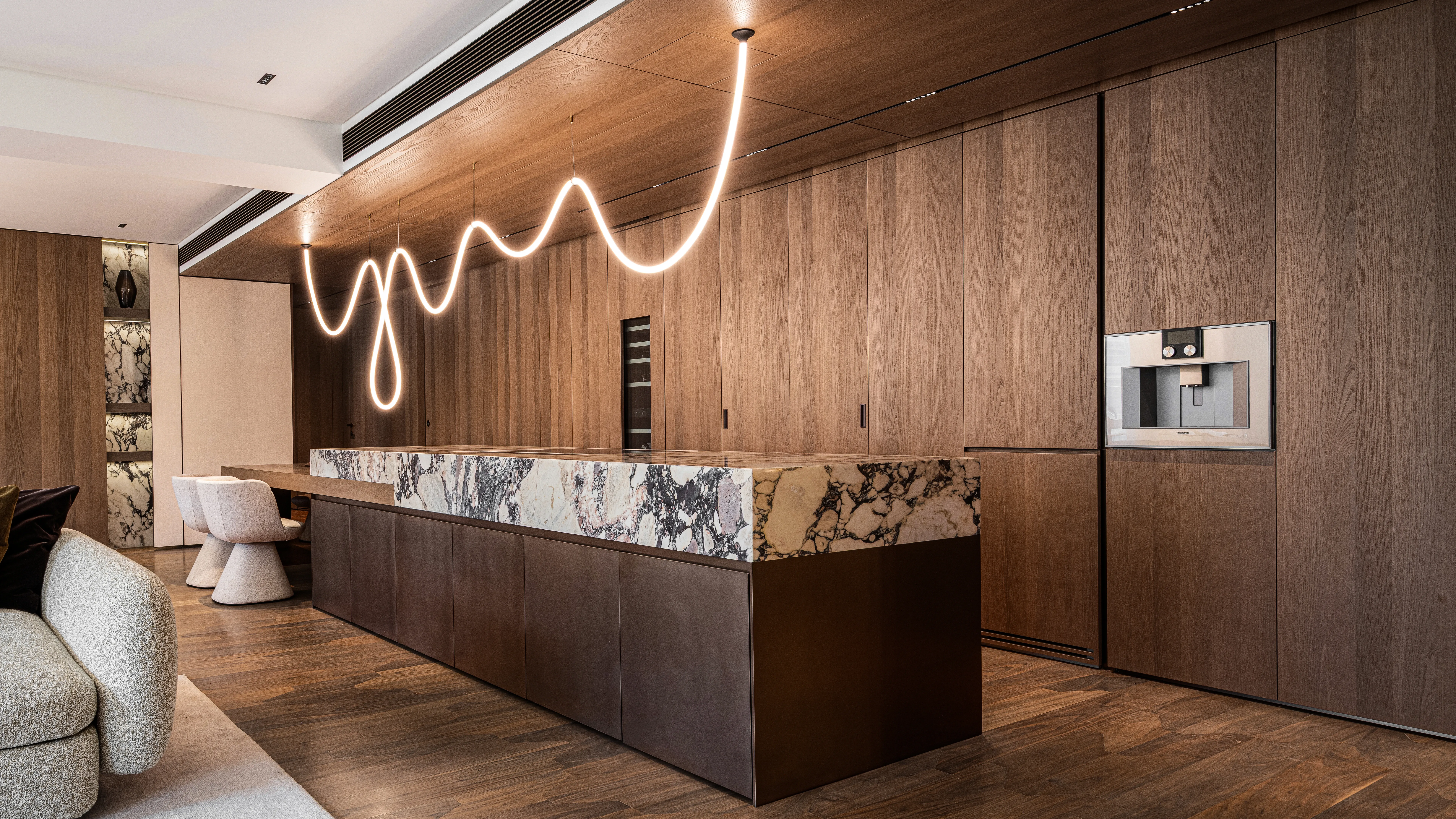 Kitchen island in veined marble under sculptural pendant light, The Amber Residence, Beijing