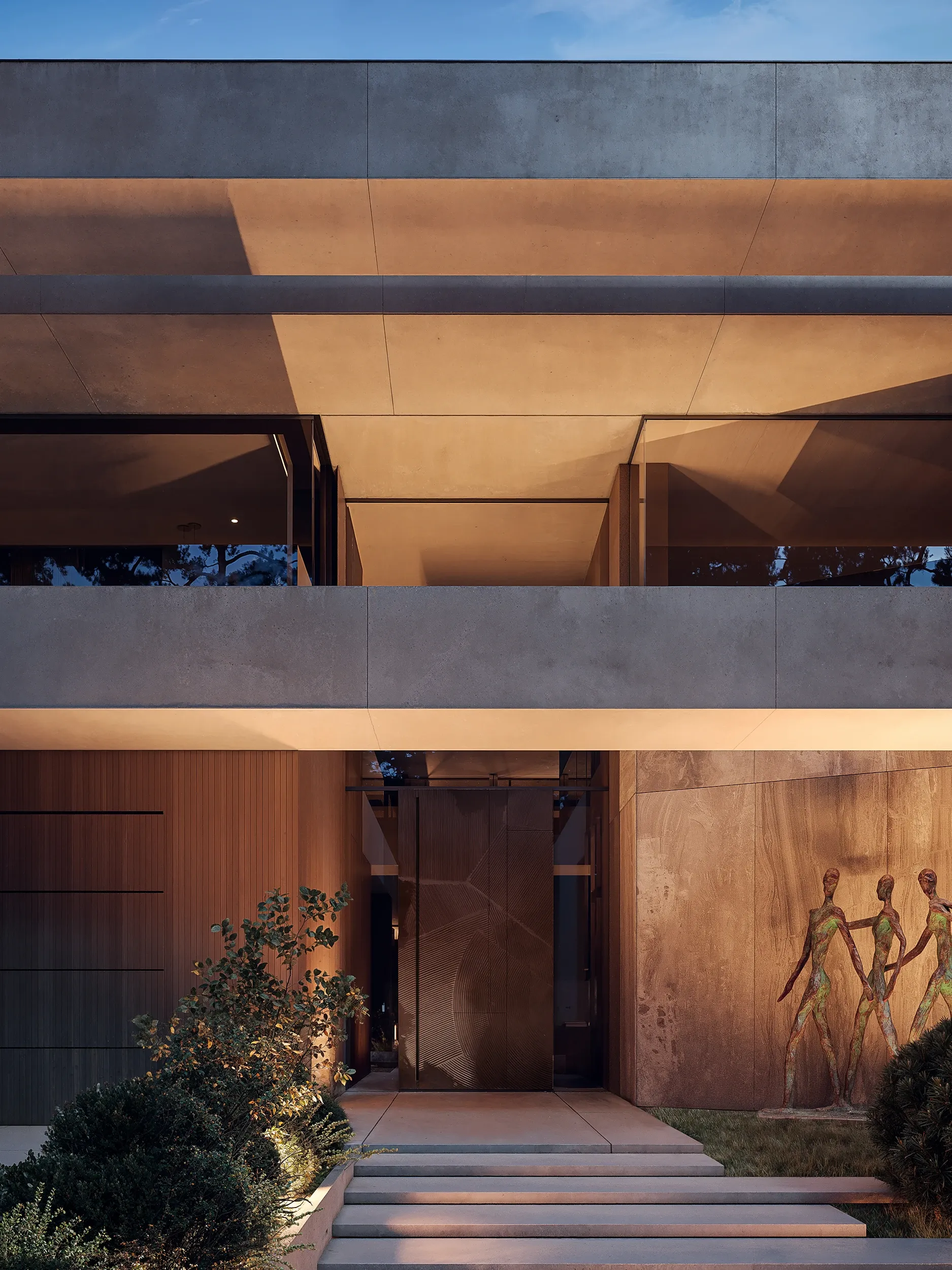 Entrance facade with concrete canopy, wood cladding and bronze sculpture relief, The Evergreen Residence, Warsaw