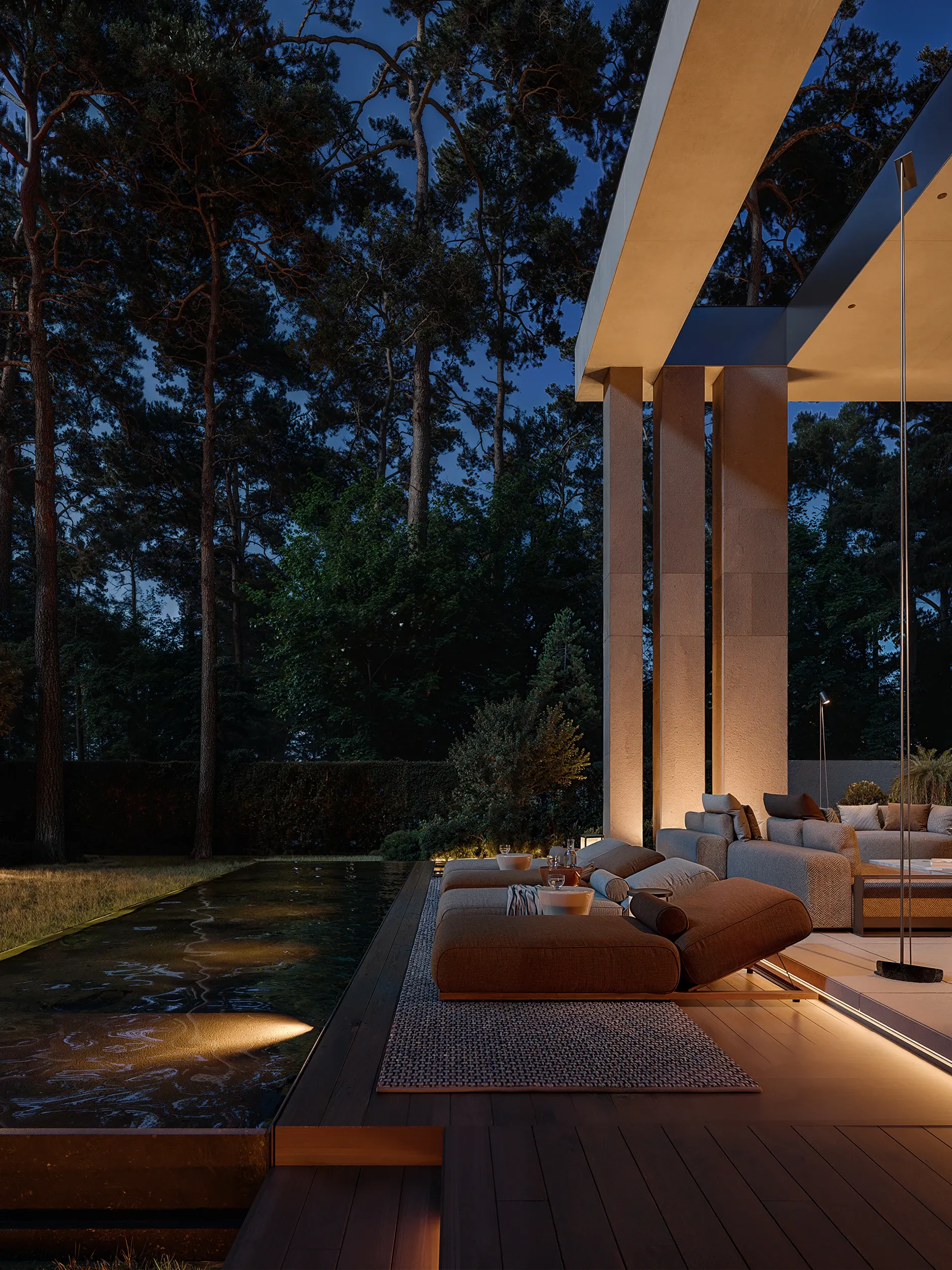 Covered terrace lounge beside reflecting pool and forest at night, The Evergreen Residence, Warsaw