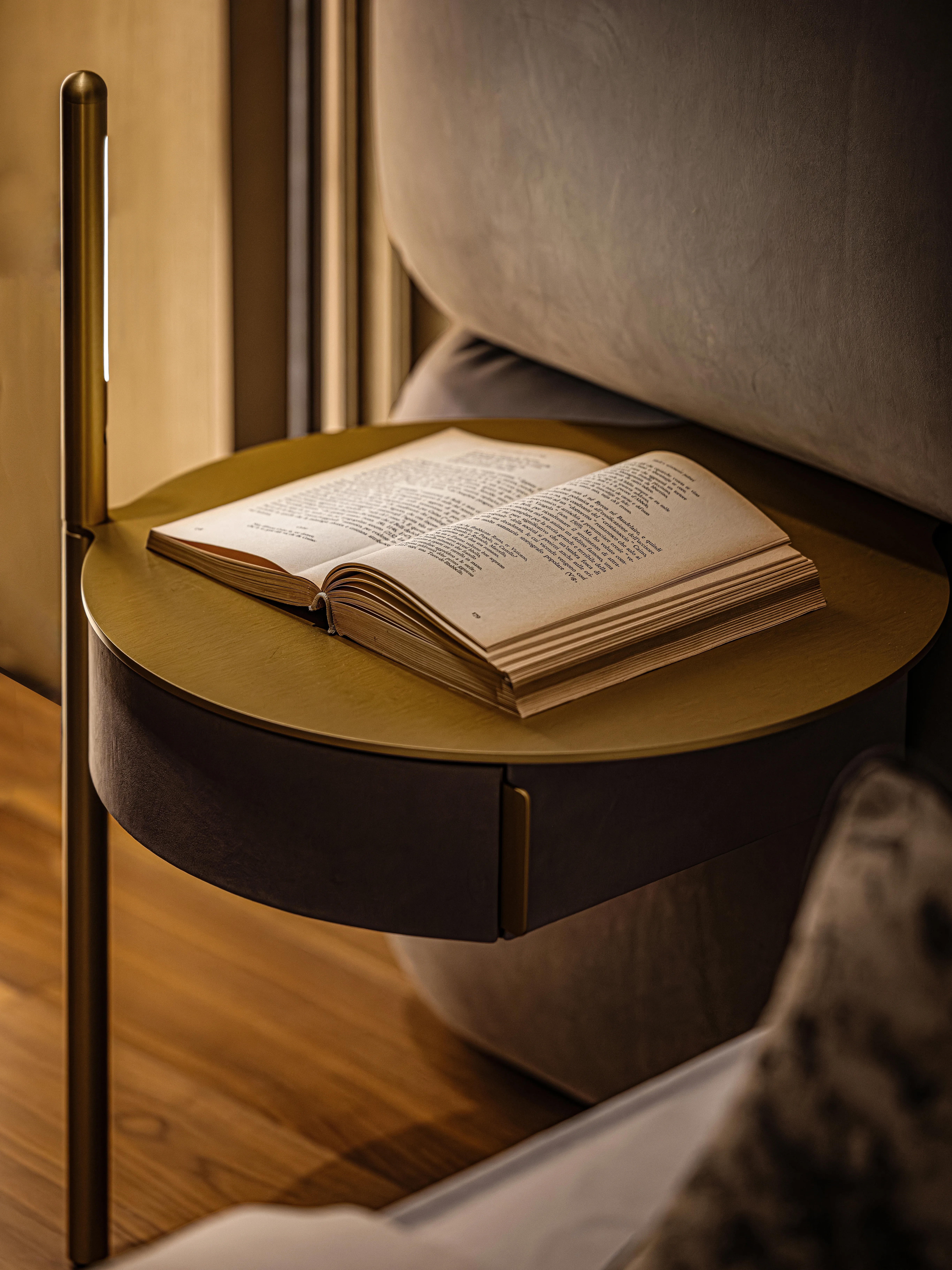 Brass bedside table with open book and slim floor lamp, The Amber Residence, Beijing