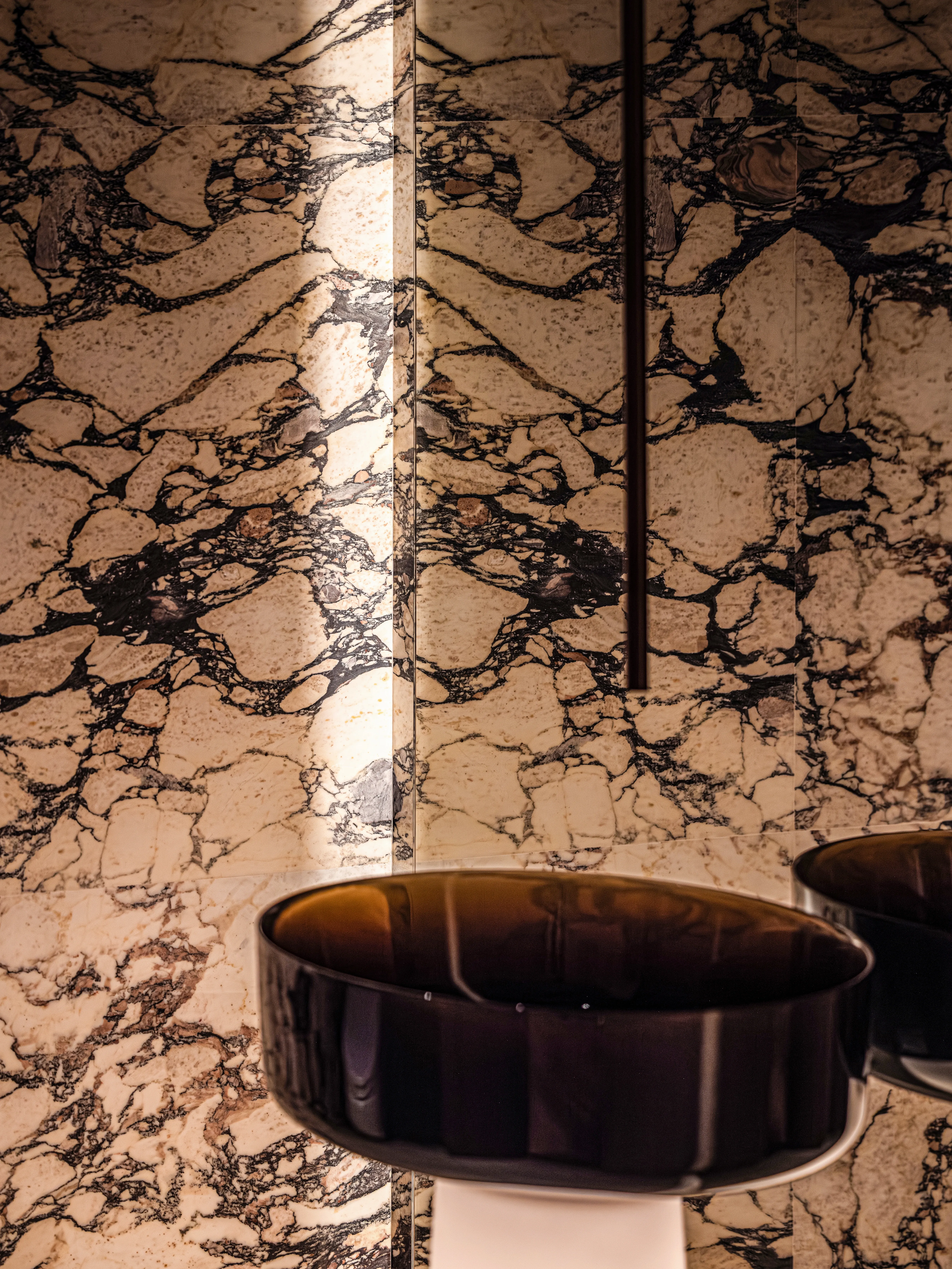 Close-up of veined marble wall and dark sink basin, The Amber Residence, Beijing