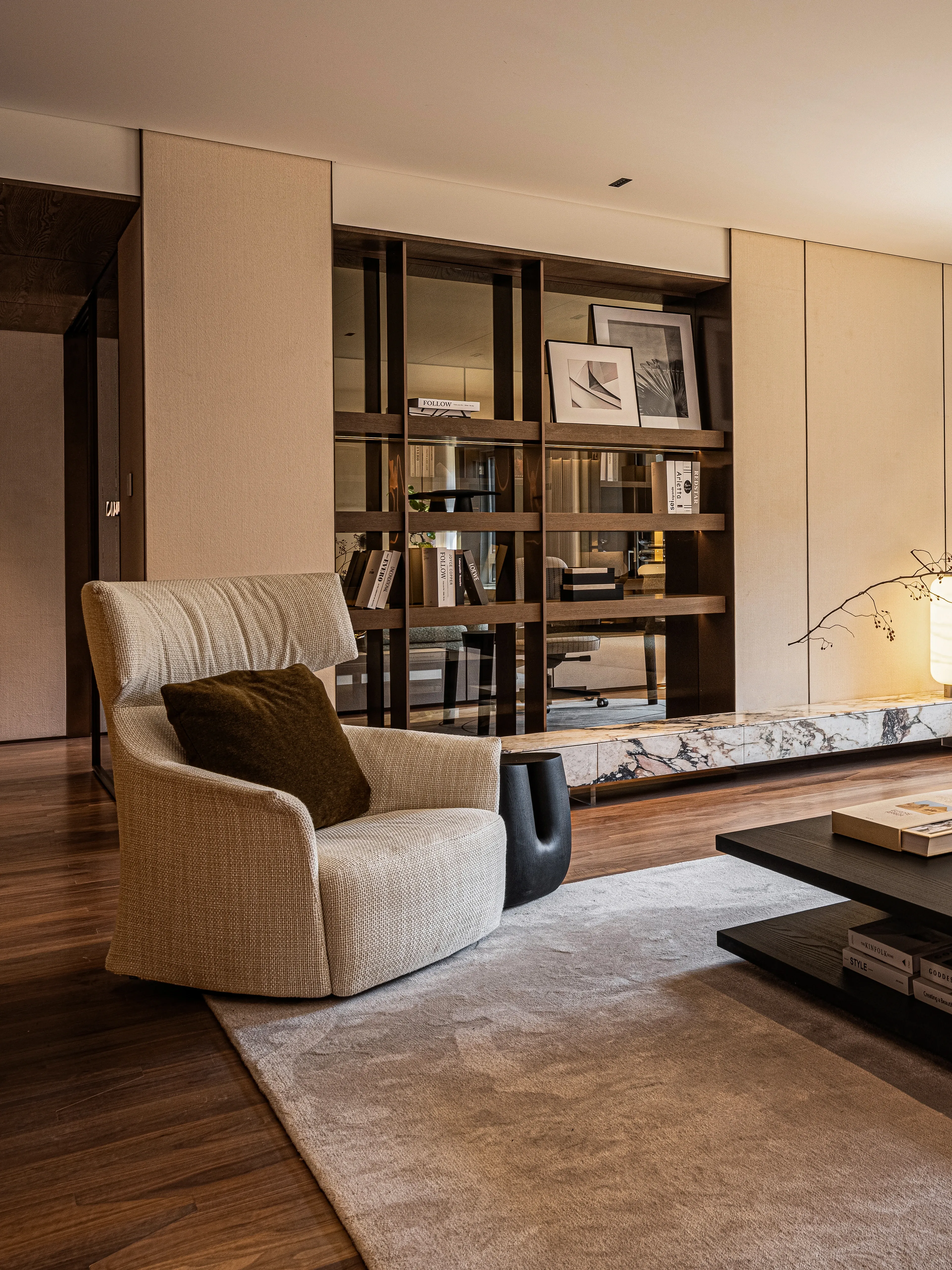 Living room with beige armchair, oak shelving and marble console, The Amber Residence, Beijing